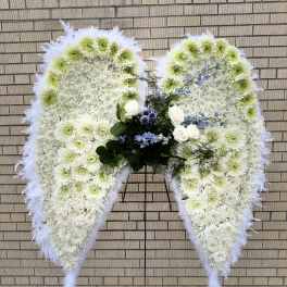 Large white floral funeral wreath shaped like angel wings