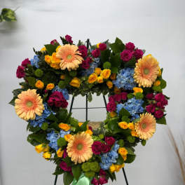 Heart-shaped floral wreath with roses, gerberas, and hydrangeas on a stand