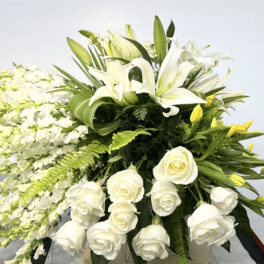 Large white floral arrangement with lilies, roses, and cascading blooms