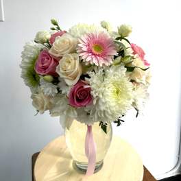 Pink and white mixed bouquet in a glass vase with a pink ribbon