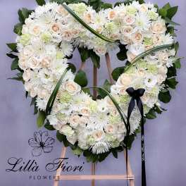 Heart-shaped floral wreath of white and blush flowers on an easel