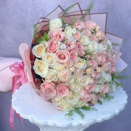 Large bouquet of pink and cream roses wrapped in pink paper