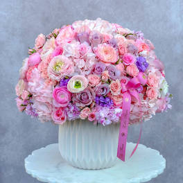 Large pink and lavender bouquet in a white vase with a ribbon