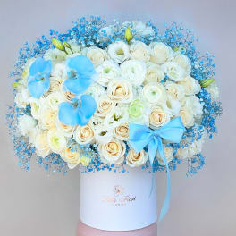 White rose bouquet with blue orchids and a blue ribbon in a white box