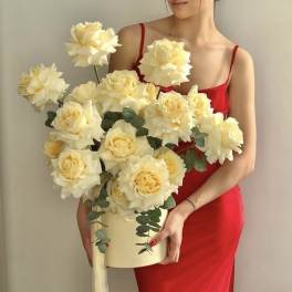 Woman in a red dress holding a cream rose arrangement in a box
