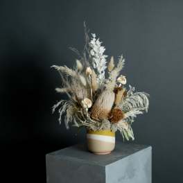 Dried floral arrangement in a striped ceramic vase