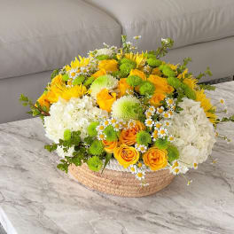 Yellow and white flower arrangement in a woven basket