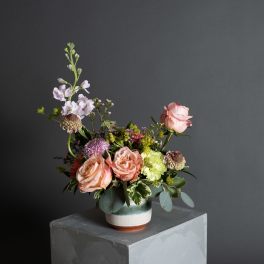 Mixed bouquet of peach and pink roses in a ceramic vase
