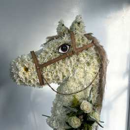 Horse-shaped floral standing display with white flowers and a small bouquet