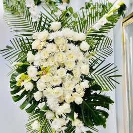 Large white floral standing spray with roses and lilies on a stand