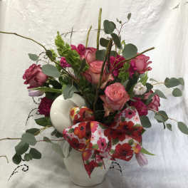 Pink roses and mixed flowers in a white vase with a floral ribbon
