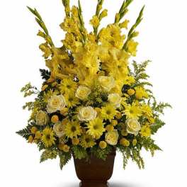 Tall yellow and white flower arrangement with gladiolus, roses, and daisies in a brown vase
