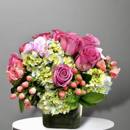 Pink roses and hydrangeas arranged in a dark glass vase