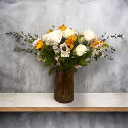 White and orange floral arrangement in a tall brown vase