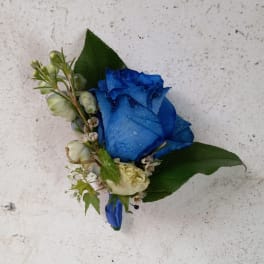 Blue rose boutonniere with small white flowers and green leaves