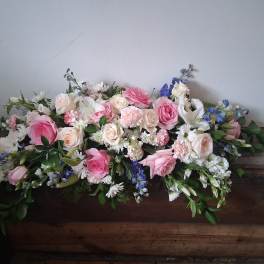 Large pink and white floral casket spray with blue accents
