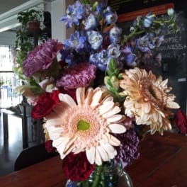 Mixed bouquet with gerbera daisies and blue-purple flowers in a glass vase