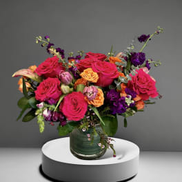 Bright mixed bouquet of roses and purple flowers in a glass vase