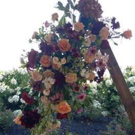 Large hanging floral arrangement with roses and mixed blooms in pink, peach, and burgundy