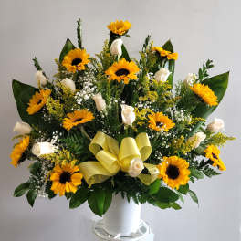 Large bouquet of yellow sunflowers and white roses in a white container