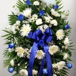 Standing funeral spray with white flowers, blue roses, and a blue ribbon