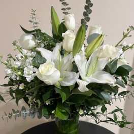 White lilies and roses arranged in a glass vase