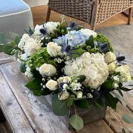 White and blue floral arrangement in a low wooden box