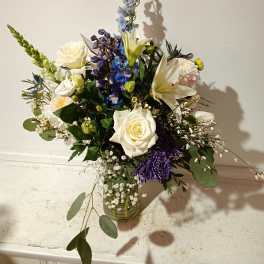 Mixed bouquet in a glass vase with white, blue, and purple flowers