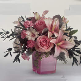 Pink roses and lilies arranged in a pink glass vase