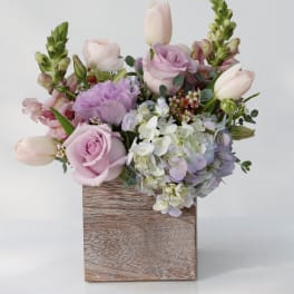 Pastel bouquet of roses, tulips, hydrangea, and snapdragons in a wooden box