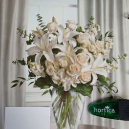 White lilies and cream roses in a clear glass vase
