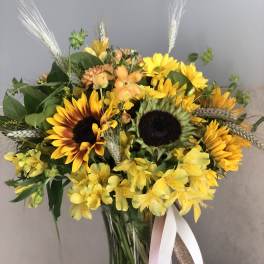 Yellow sunflower bouquet in a glass vase with ribbon