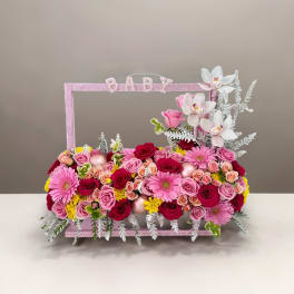 Pink and white floral baby gift arrangement with roses and orchids