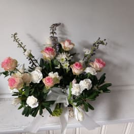 Pink and white rose arrangement with white ribbon in a basket