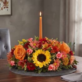 Autumn floral centerpiece with a lit orange taper candle
