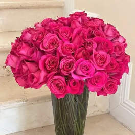 Bouquet of bright pink roses in a tall glass vase