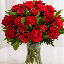 Red roses and carnations in a clear glass vase