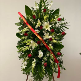 Standing floral spray with red roses, white lilies, and a red ribbon