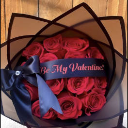 Bouquet of red roses wrapped in black paper with a navy ribbon