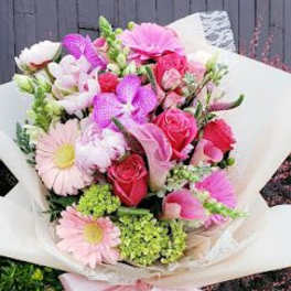 Pink and white mixed bouquet wrapped in white paper with a ribbon