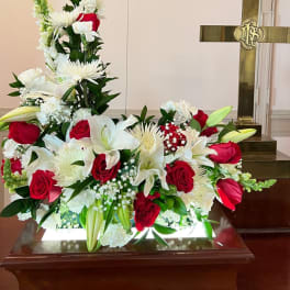 Red and white funeral spray with roses, lilies, and a cross