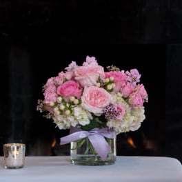 Pink rose bouquet in a glass vase with a lavender ribbon