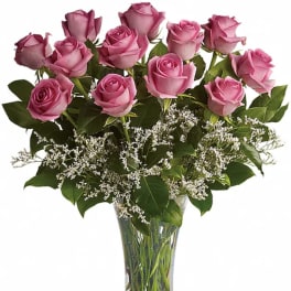 Pink roses arranged in a clear glass vase with white filler flowers