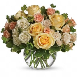 Mixed roses in cream, blush, and yellow arranged in a clear glass vase