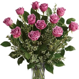Bouquet of pink roses with mixed greenery in a clear glass vase