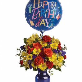 Birthday balloon above a colorful flower arrangement in a blue vase