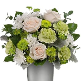 Bouquet of pale roses, green carnations, and white daisies in a gray vase