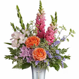 Mixed bouquet with orange roses, pink snapdragons, and purple flowers in a silver vase