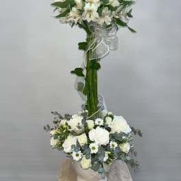 Tall white floral arrangement with a lower white bouquet in a vase