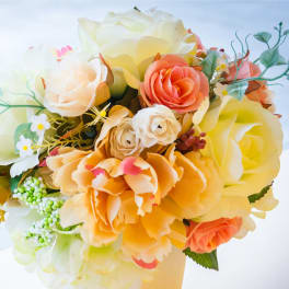 Bouquet of cream, peach, and yellow roses with small white accents